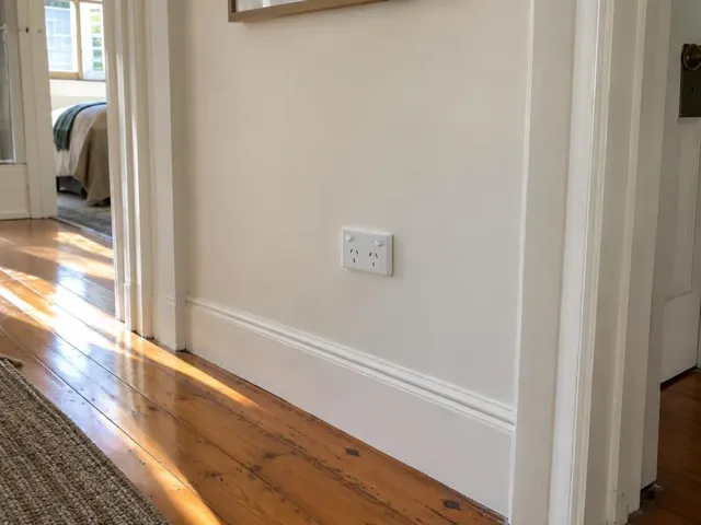 White wall power point on a painted hallway wall with timber floors in Kensington